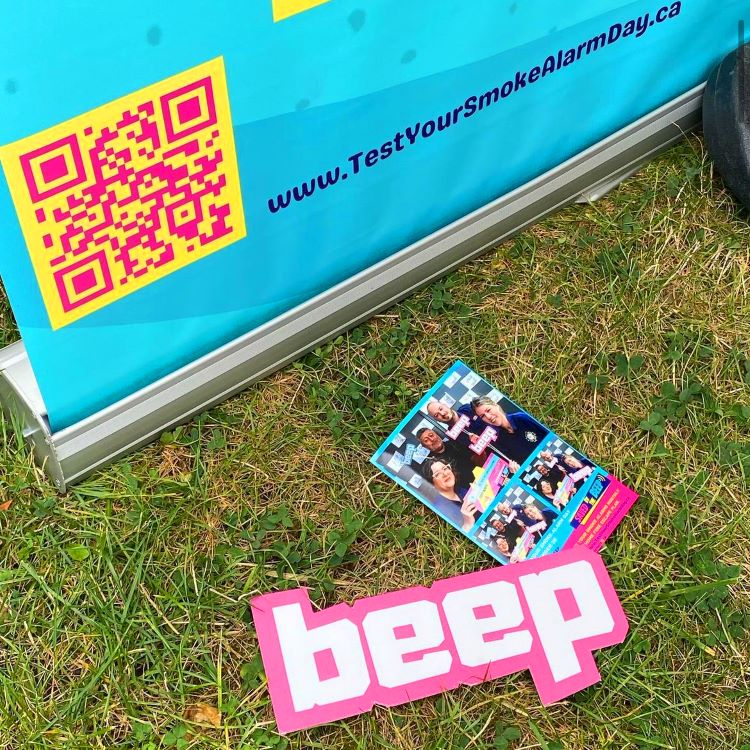 Picture of photo print out and a WordArt sign with the word ‘beep’ laying on the grass at the Canadian National Exhibition by Office of the Fire Marshal promoting this year’s Saved By the Beep fire safety campaign.